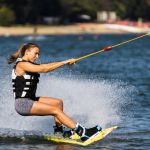 Female wakeboarder wakesurfing. Girl riding waterski cabel. Holding tow rope. Summer activities in the lake.